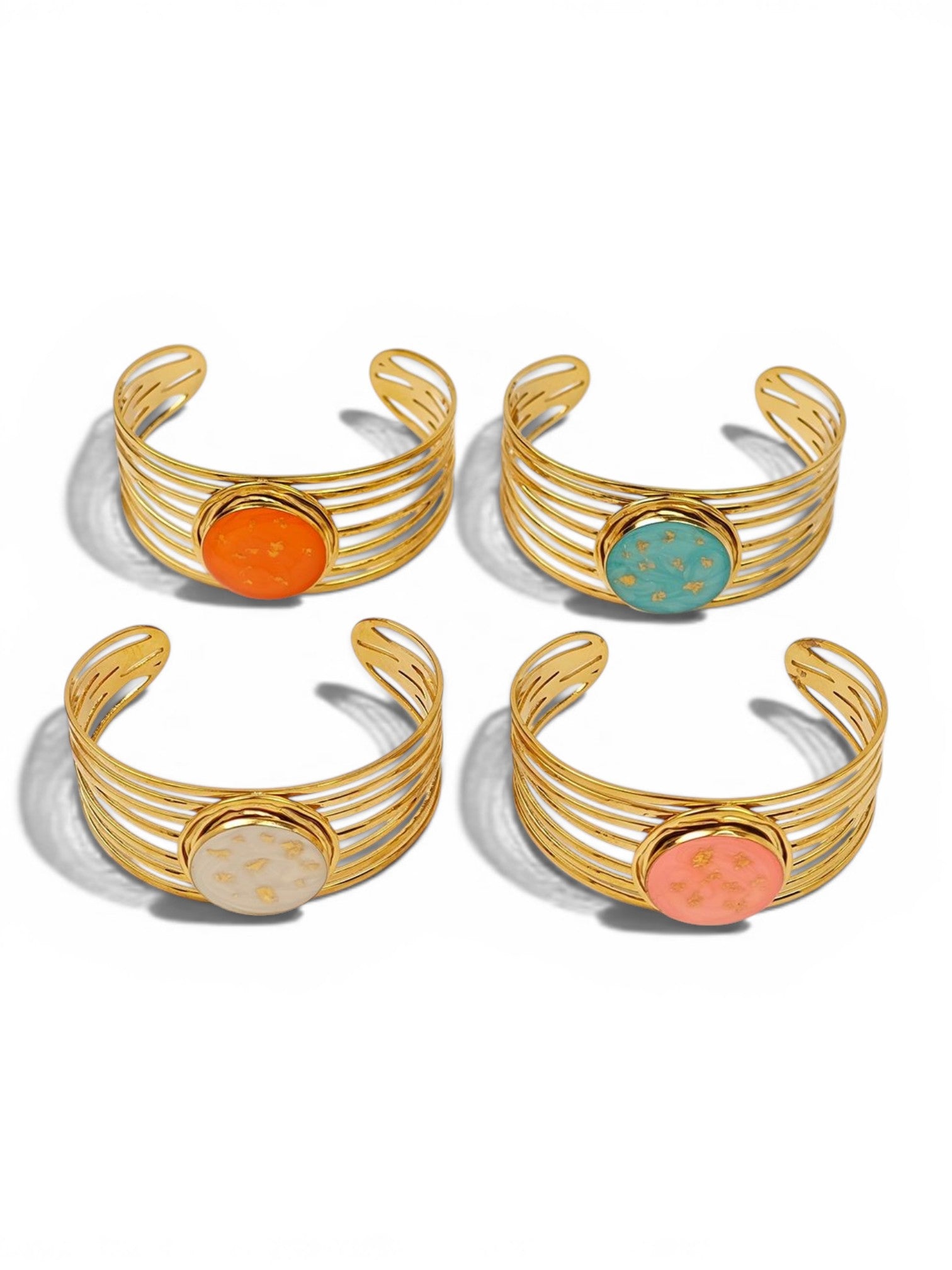 Four gold cuff bracelets with colorful stones on a white background