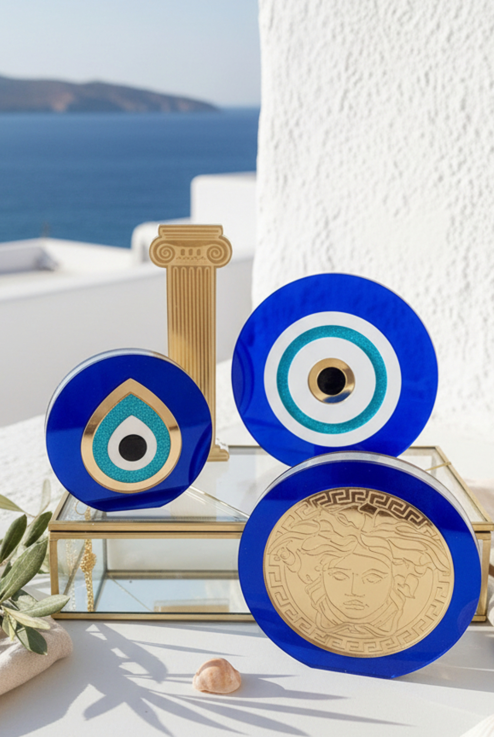 Σετ από μπλε plexiglass γούρια μάτι και χρυσές λεπτομέρειες σε κυκλαδίτικη ταράτσα με θέα θάλασσα