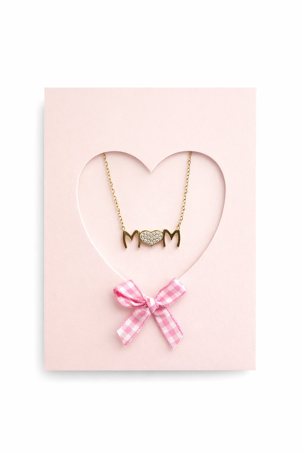 Gold necklace with 'MOM' pendant on a pink heart-shaped card with a pink bow.