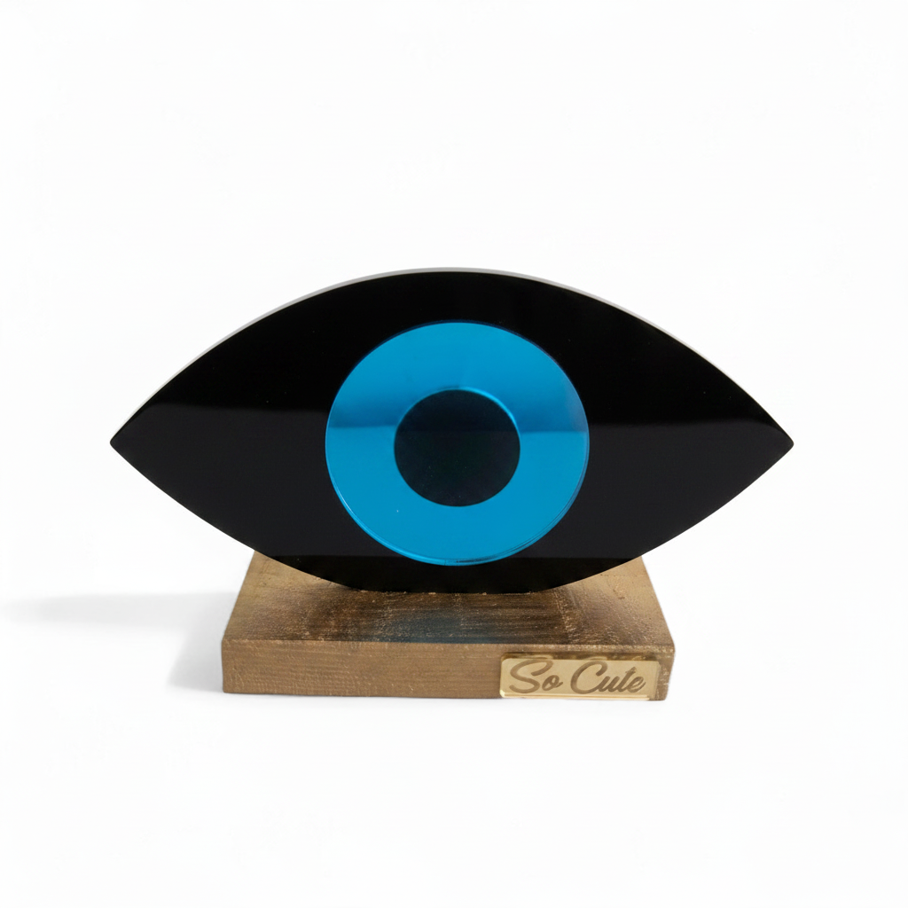 Decorative eye-shaped object with a blue center and black outer rim on a wooden stand, branded 'So Cute'.