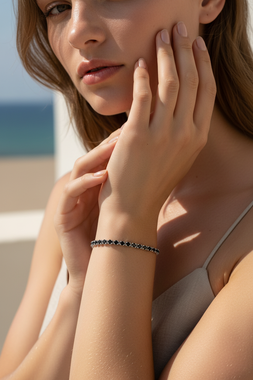 Woman wearing a black tennis bracelet with a blurred beach background
