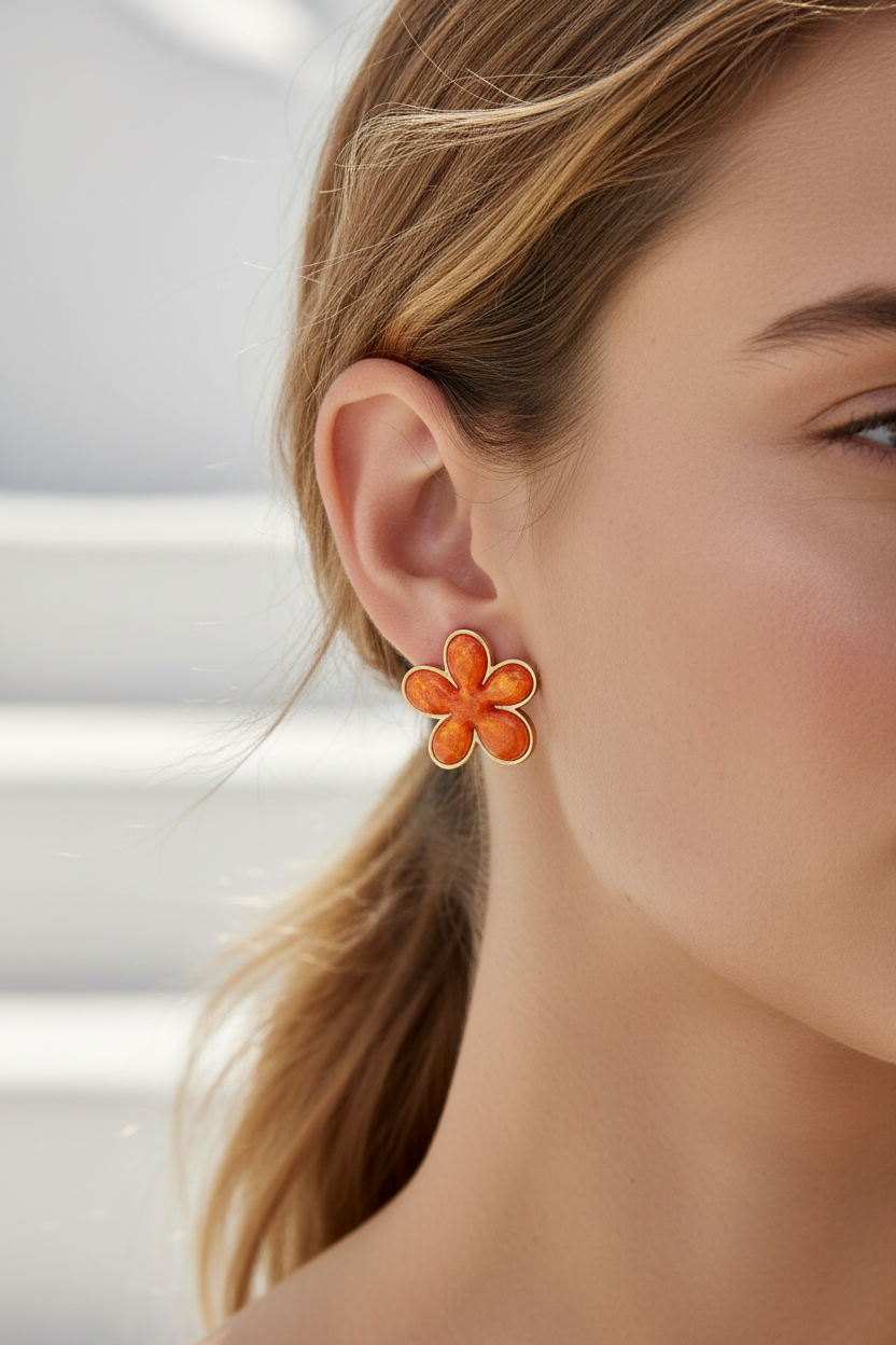Close-up of a woman wearing orange flower-shaped earrings with a blurred background.