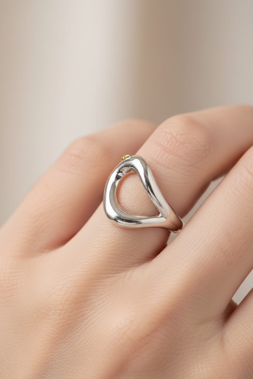 Silver ring on a finger against a neutral background