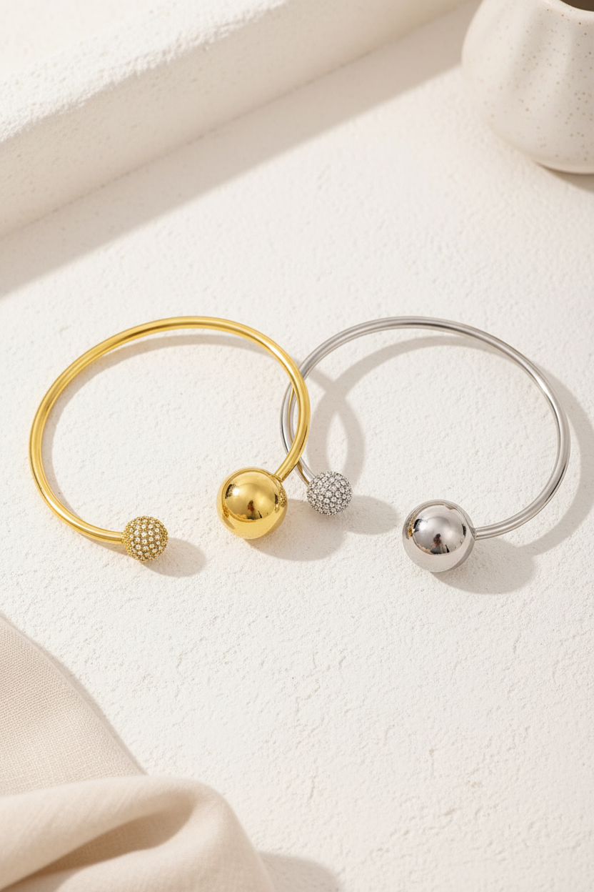 Sphere Glow Bangle σε χρυσό και ασημί χρώμα, ατσάλινο βραχιόλι bangle με μπίλιες και ζιργκόν σε minimal flatlay