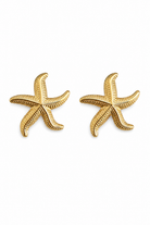 A pair of gold starfish stud earrings on a plain white background.