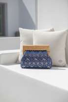 Blue lace clutch bag on a white surface with pillows in the background