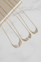 Gold necklaces with leaf-like pendants on a marble surface