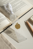 Clear bookmark with gold apple design on an open book