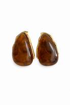 Γυναικεία σκουλαρίκια Amber Glow με χρυσό ανοξείδωτο ατσάλι και καφέ εφέ ταρταρούγας σε λευκό φόντο.