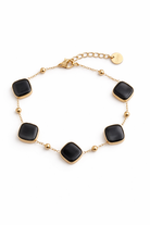 Gold steel bracelet with black square stones on a white background