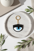 Keychain with eye design on a round marble coaster with leaves around