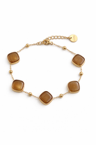Gold steel bracelet with brown square stones on a white background