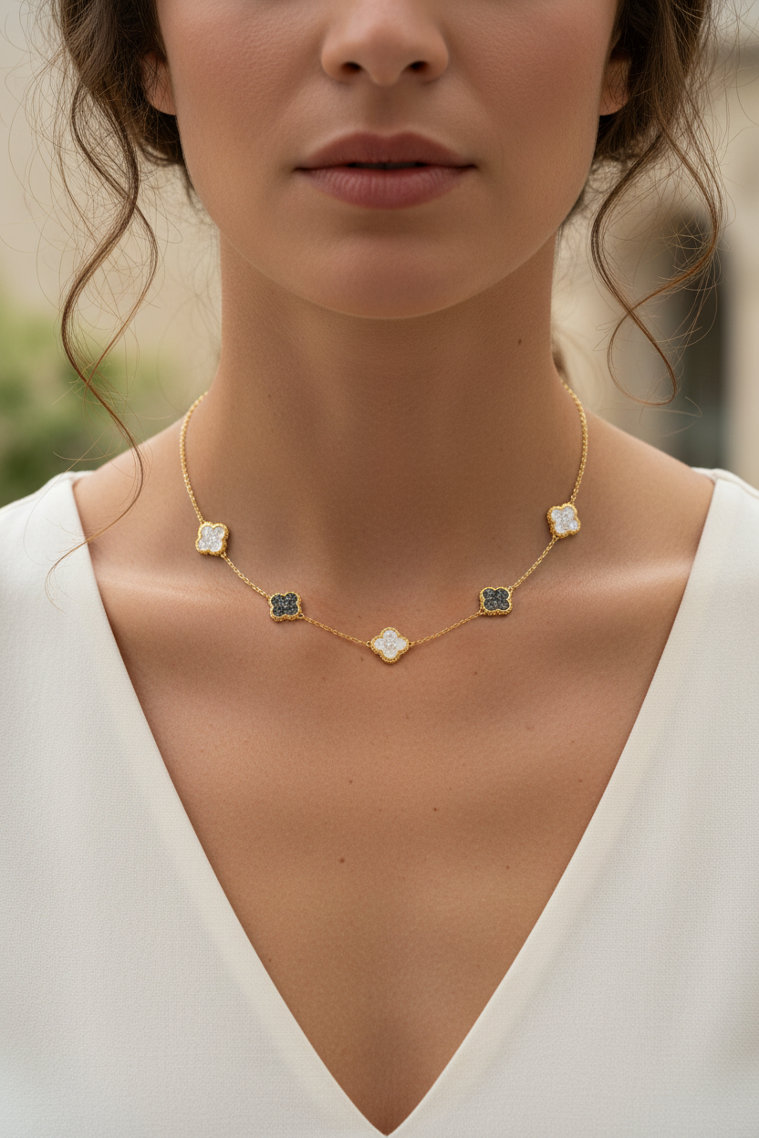 Woman wearing a delicate gold necklace with black and white stones against a neutral background