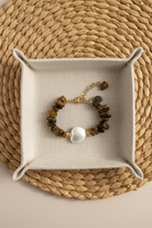 Bracelet with brown beads and a pearl on a woven mat