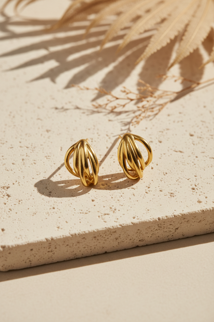 Contour Sculptural Earrings σε χρυσό χρώμα με γλυπτικό μεταλλικό σχέδιο σε minimal flatlay