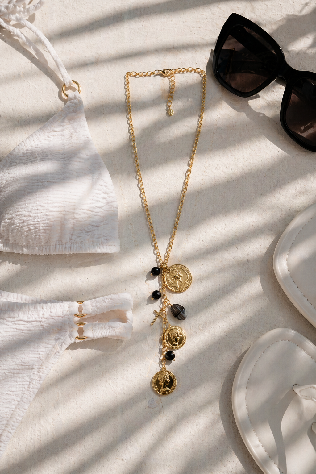 Élira Coin Y Necklace μαύρο χρυσό σε καλοκαιρινό flatlay με bikini και γυαλιά ηλίου