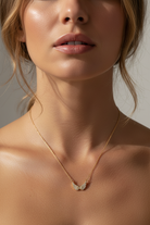 Close-up of a woman wearing a delicate necklace with a neutral background