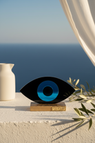 Decorative eye sculpture with blue center on a white surface near a body of water