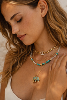 Woman wearing multiple necklaces with a focus on an elephant pendant.