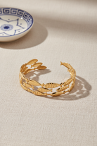 Gold stainless steel bracelet with fish designs on a white background, So Cute by Dimi