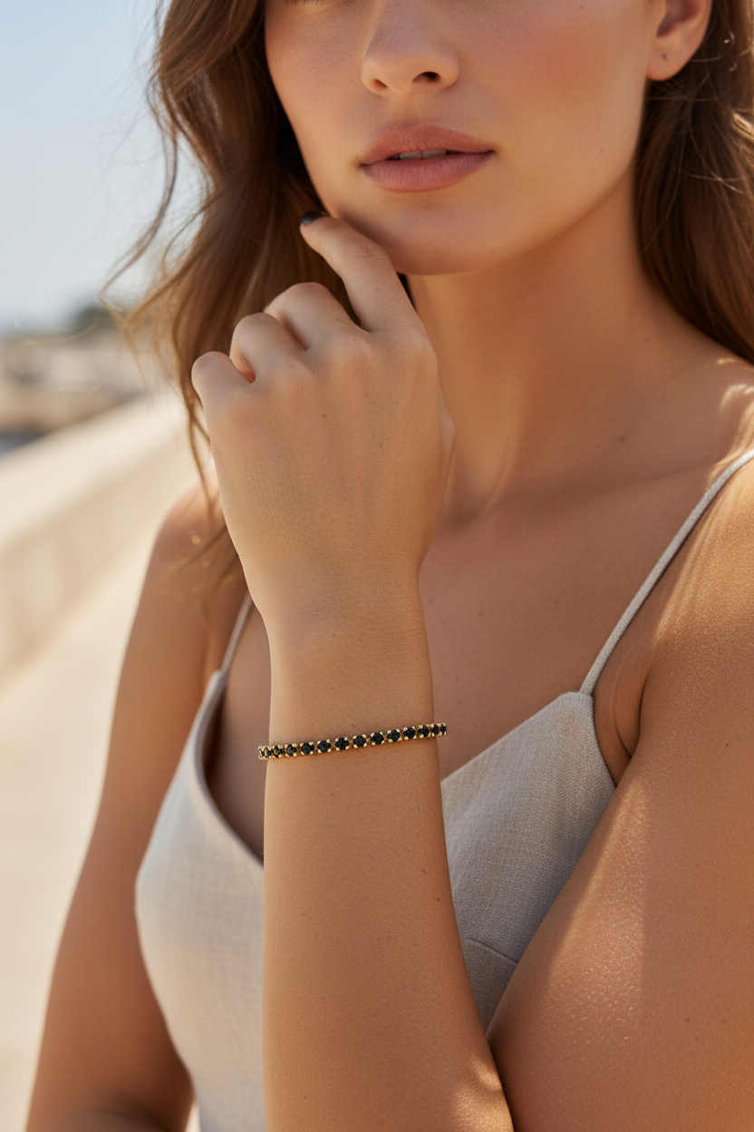 Woman wearing a black stainless steel tennis bracelet on a blurred beach background