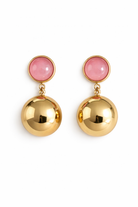 Gold earrings with pink gemstones on a white background
