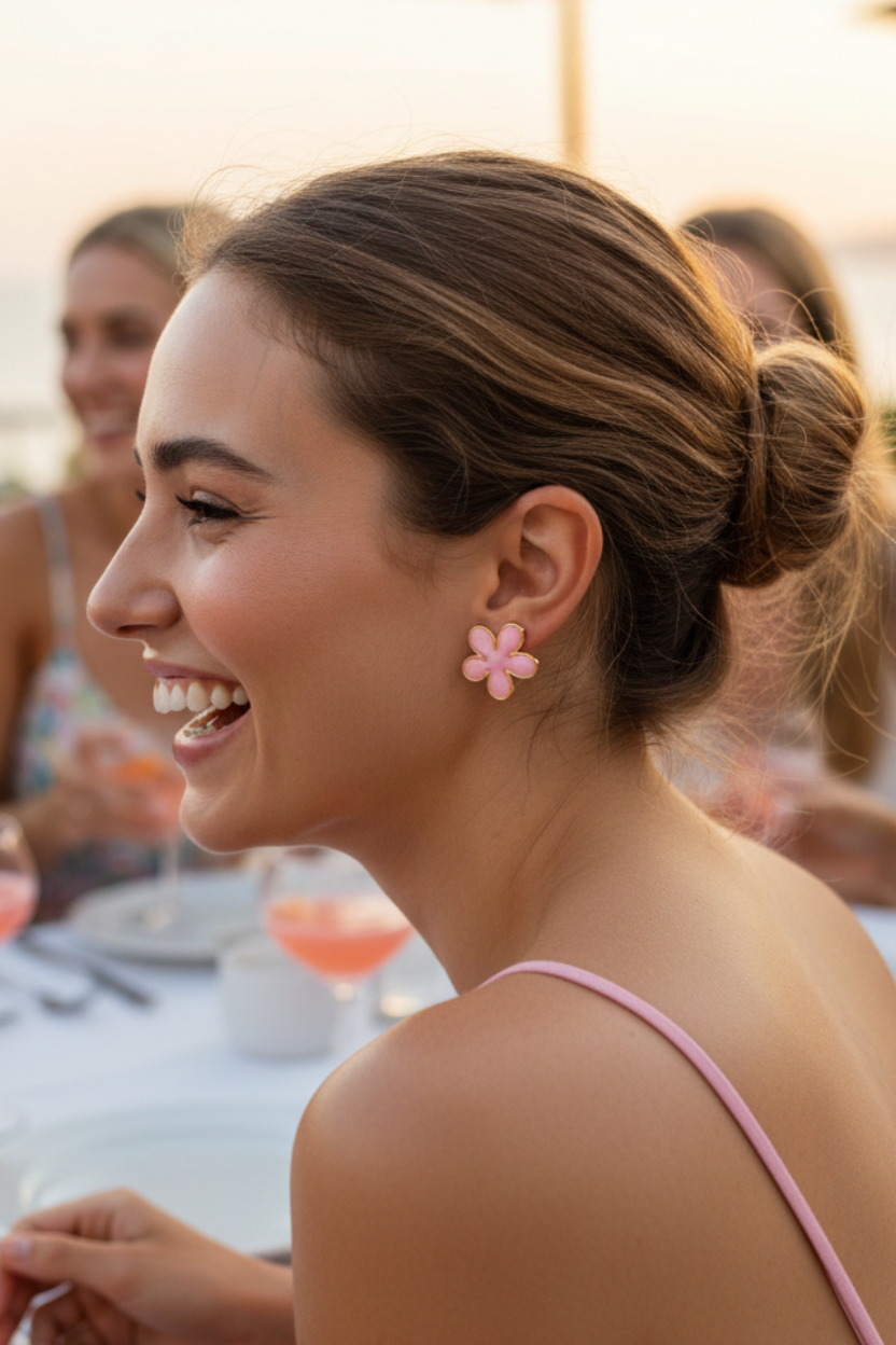 Woman with a bun and flower earrings smiling outdoors