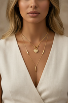 Woman wearing layered silver necklaces with a neutral background