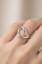 Silver ring on a finger against a neutral background