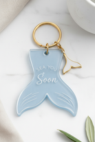 Blue whale tail keychain with 'Sea You Soon' text on a white surface.