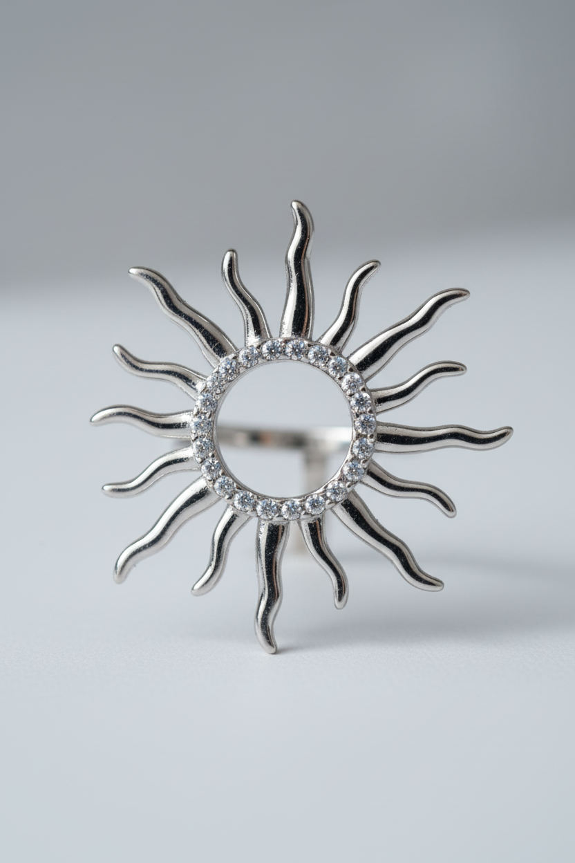 Silver sun-shaped ring with rhinestones on a light gray background