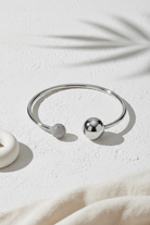 Sphere Glow Bangle σε ασημί χρώμα, ατσάλινο βραχιόλι bangle με ζιργκόν σε minimal stone flatlay