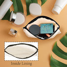 Makeup pouch with cosmetic items on a beige background with green leaves